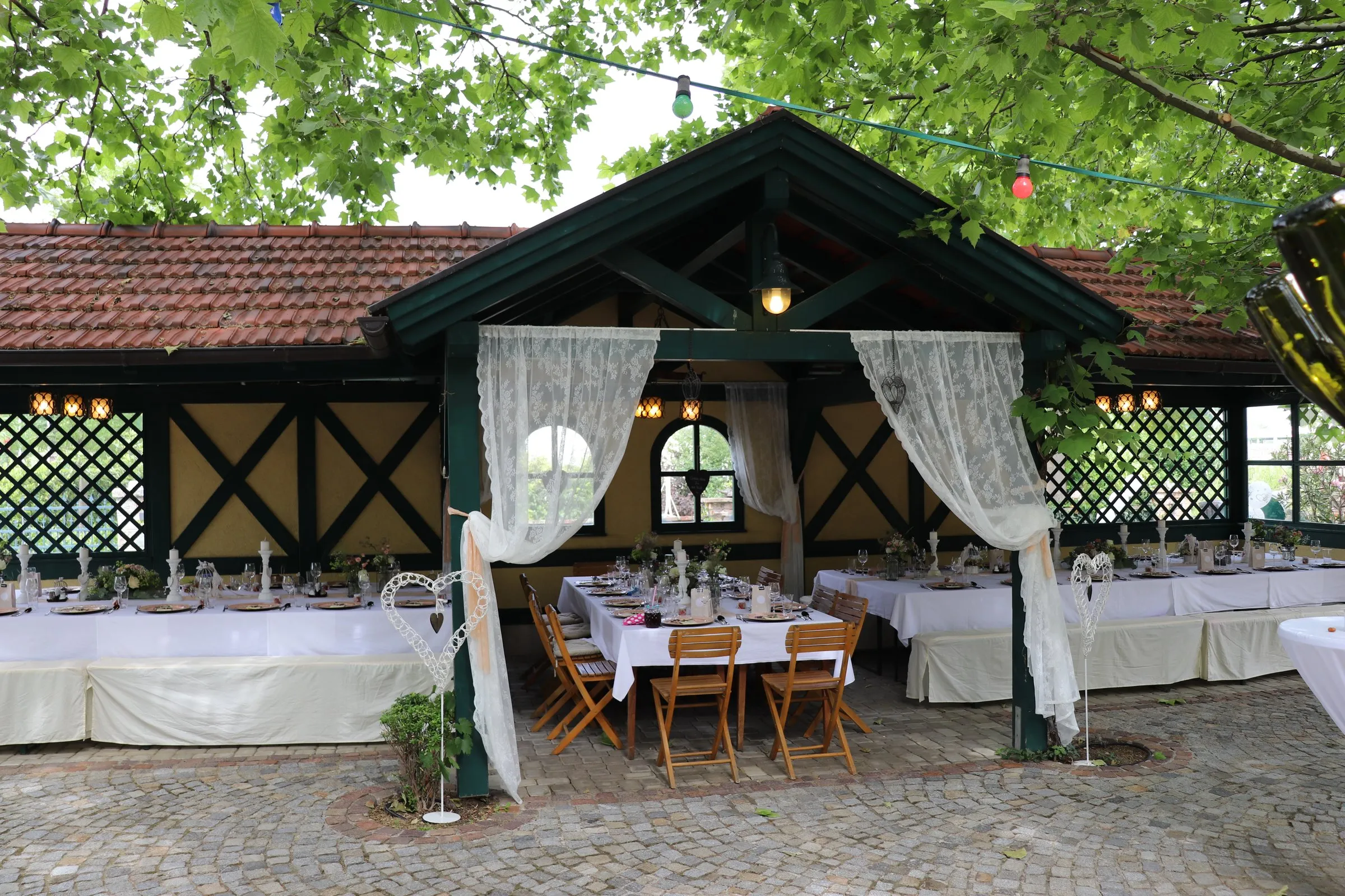 Überdachter Holzpavillon im Garten, festlich weiß gedeckte Tafel